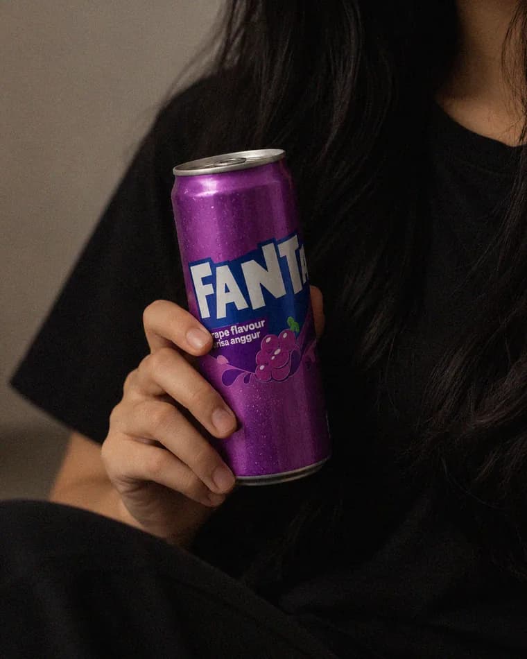 Hand holding a can of Fanta grape